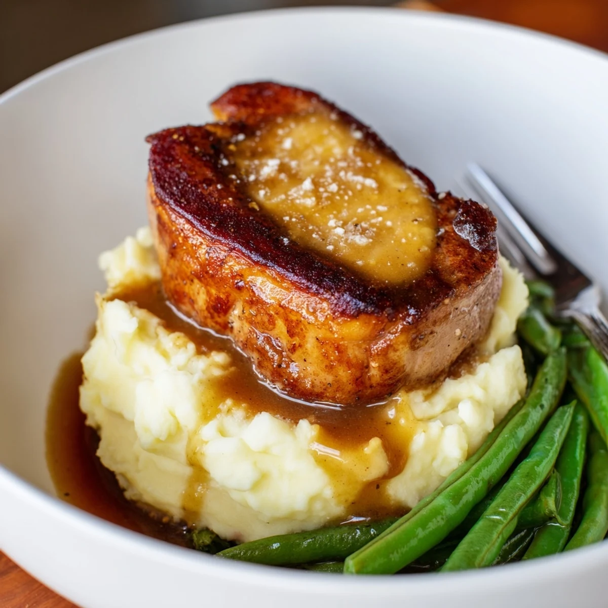 Comforting pork chops and cheddar mash bowl, garnished with crisp green beans.