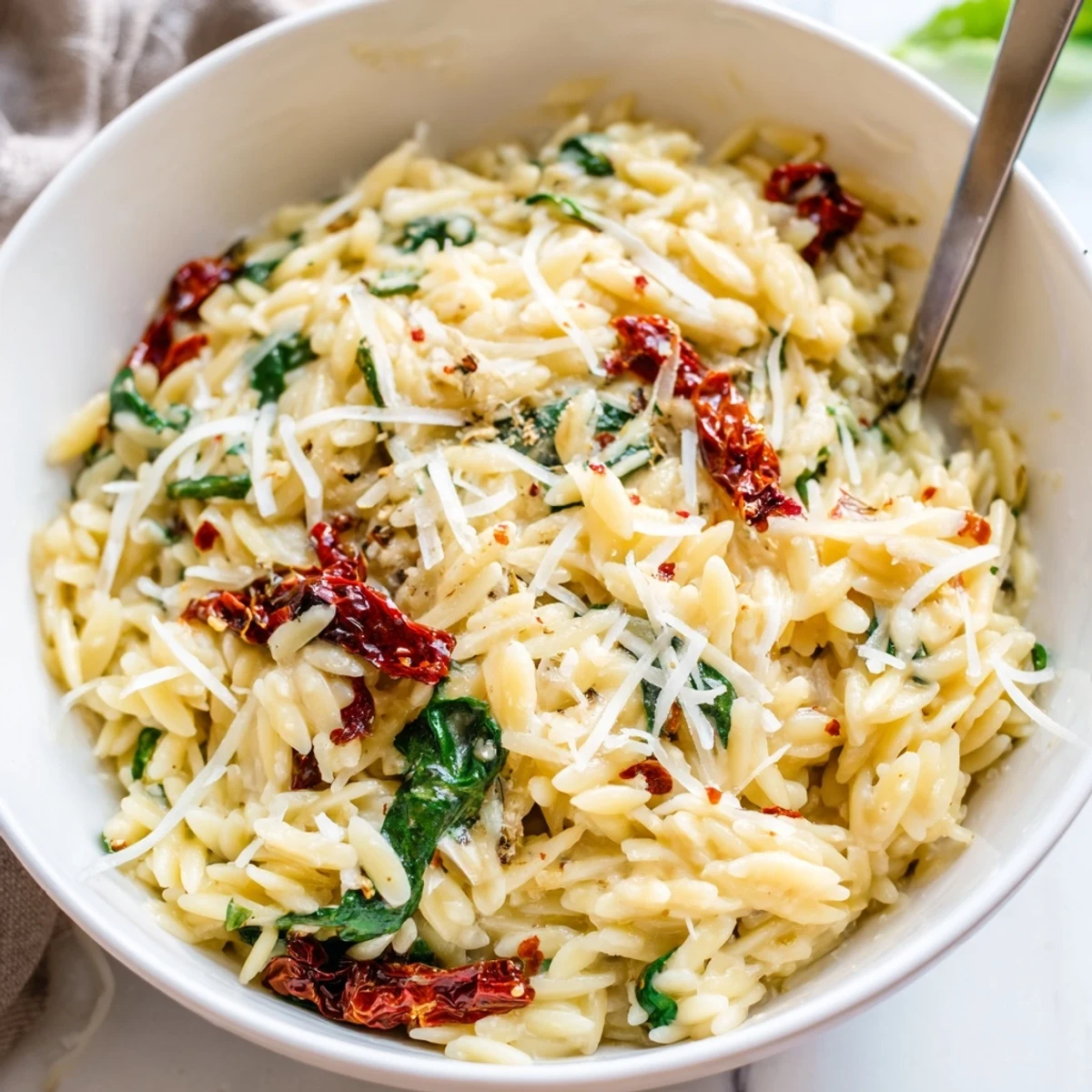 A deliciously rich Creamy Tuscan Orzo Bowl featuring garlic-Parmesan sauce and vibrant herbs.