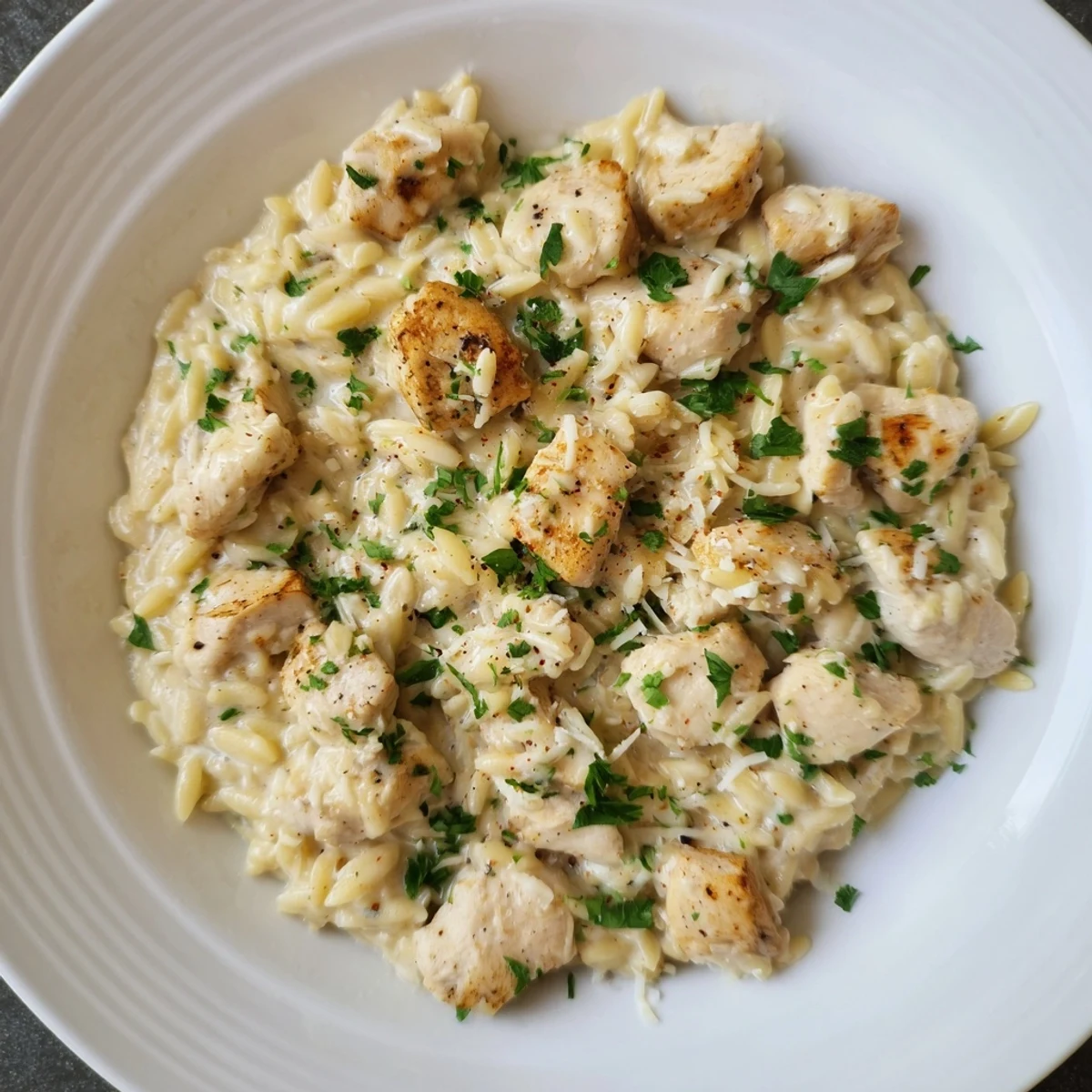 A photo of the creamy One-Pot Cajun Chicken Alfredo Orzo, with parmesan cheese and parsley garnish.