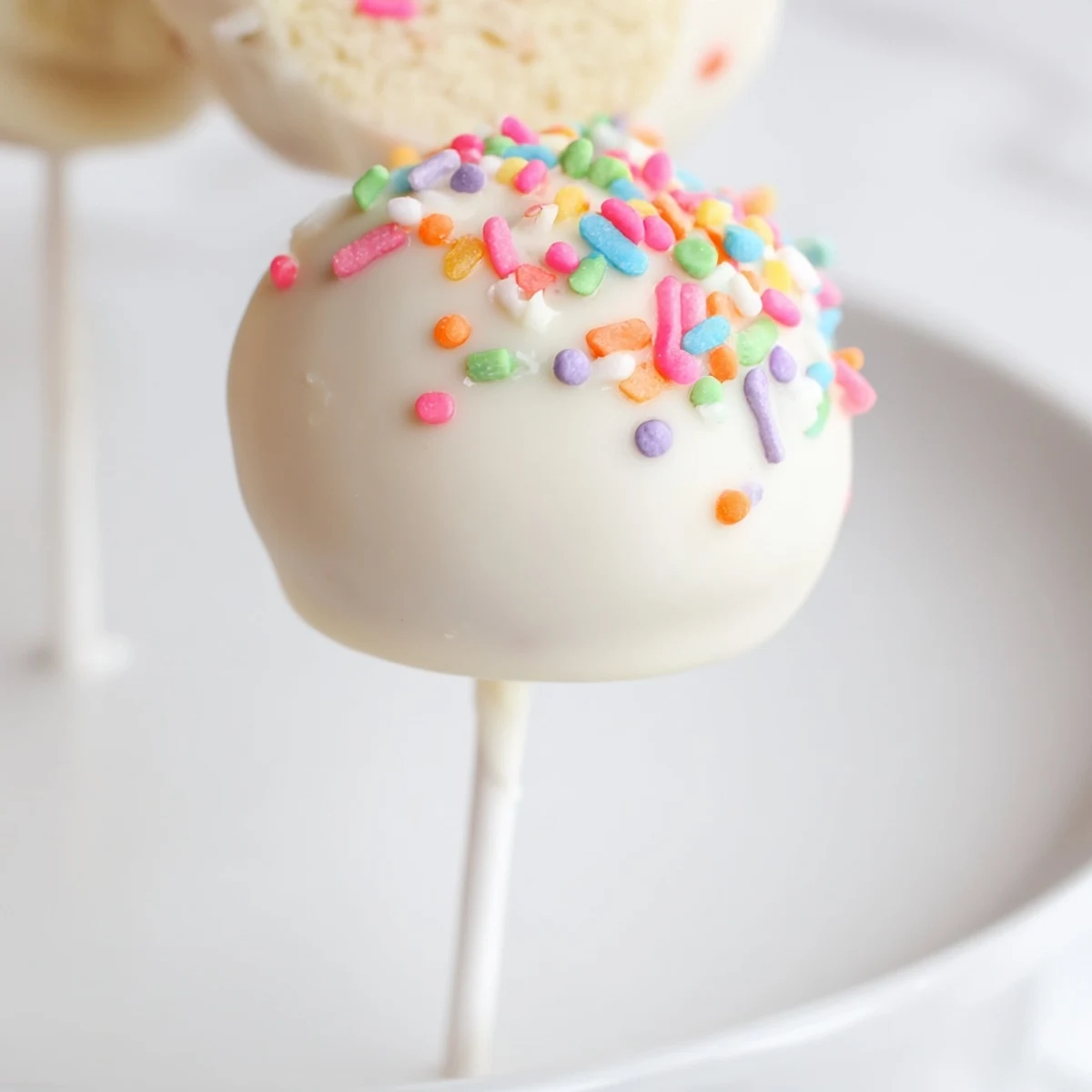Golden, bite-sized Lightened-Up Sugar Cookie Cake Pops, ready to be enjoyed, covered in sprinkles.