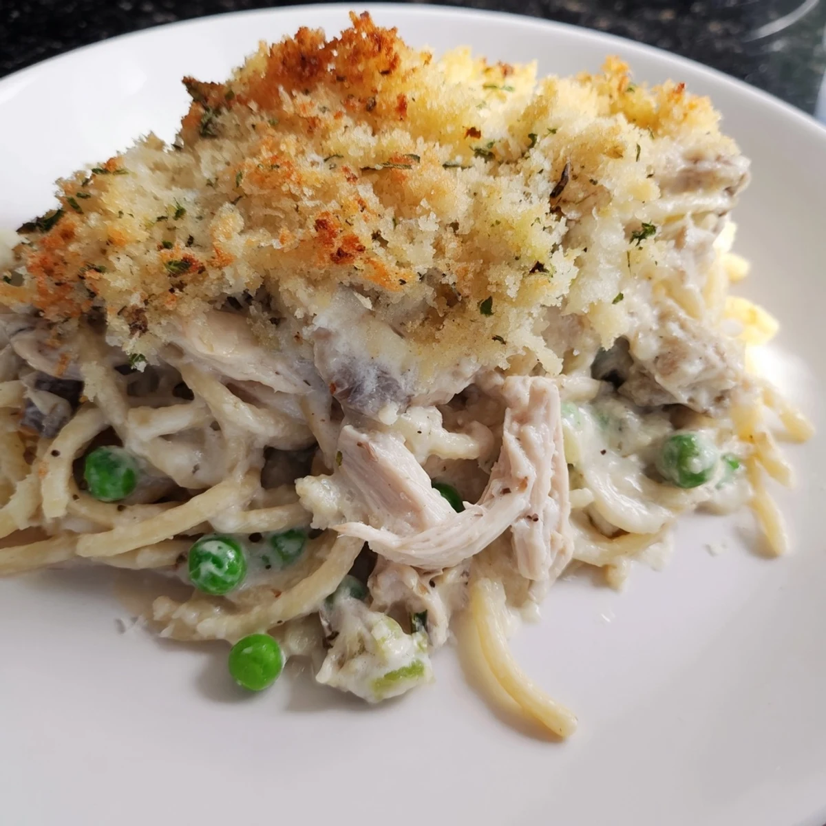 Golden-crusted Turkey Tetrazzini bake, filled with creamy pasta, tender turkey, and sweet peas, ready to serve.