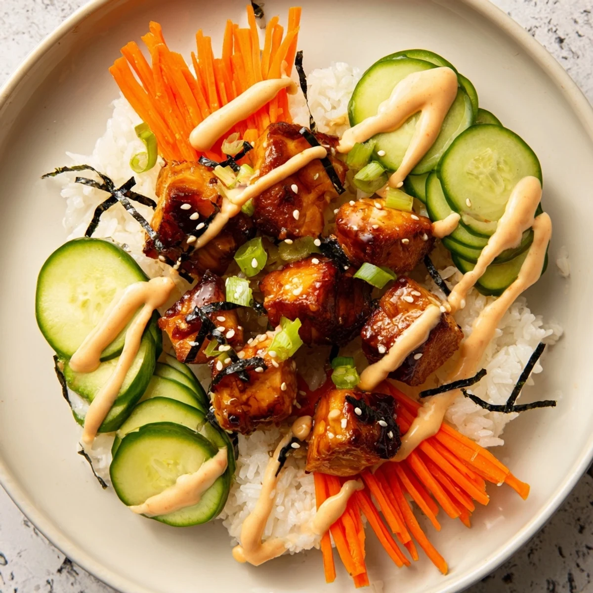 A delicious, homemade teriyaki salmon rice bowl, drizzled with spicy mayo and sprinkled with sesame seeds.
