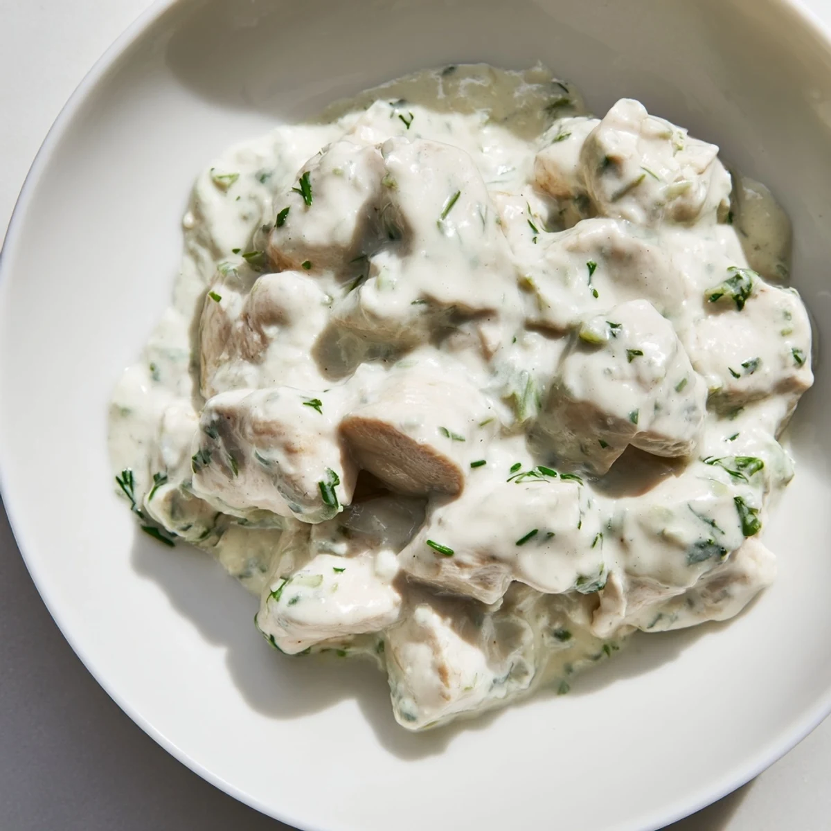 A vibrant platter of Green Goddess Chicken Salad featuring tender chicken, herbs, and a luscious yogurt-based dressing.