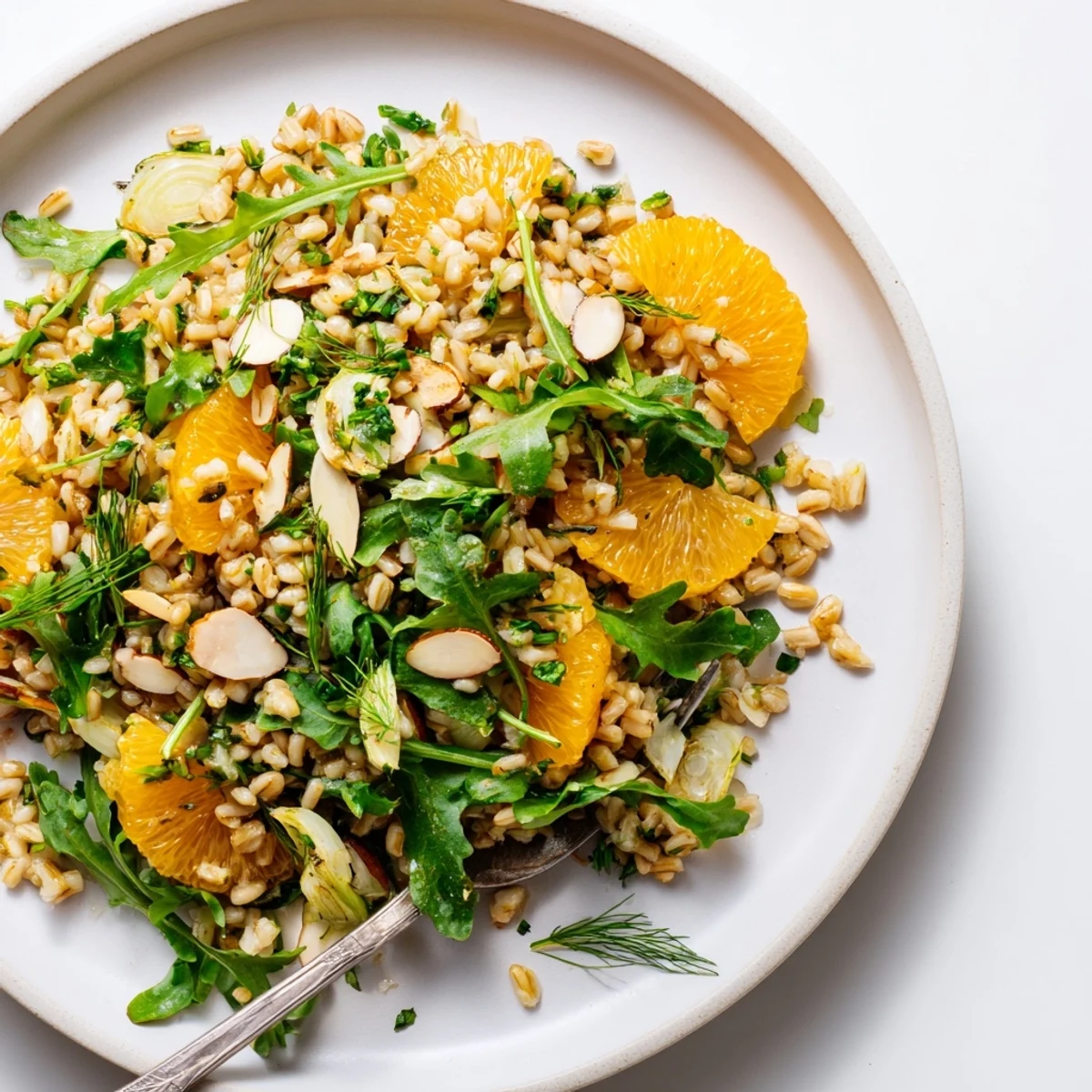 Healthy Mediterranean farro salad featuring crisp fennel, sweet oranges, and crunchy almonds, served over a bed of arugula.