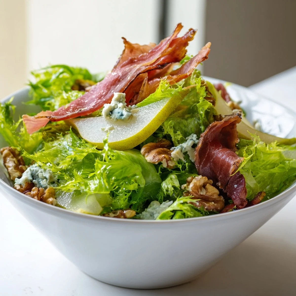 Crispy prosciutto shards top a vibrant salad of frisée, juicy pears, and crumbled blue cheese, drizzled with tangy vinaigrette.