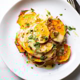 Close-up of warm, layered Cajun Sweet Potato Gratin, cheese melted, garnished with fresh parsley.