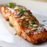 Caramelized salmon fillets brushed with honey garlic butter, resting on a baking tray ready to be enjoyed.