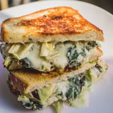 Spinach Artichoke Grilled Cheese with melty mozzarella, crisp sourdough, and a side of tomato soup on a cozy table.