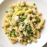 A close-up of tender chicken and peas in a creamy garlic butter sauce, served over curly pasta for a comforting dinner.