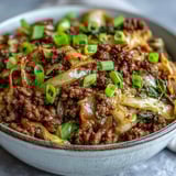 A close-up of Chinese Ground Beef and Cabbage Stir-Fry, garnished with green onions and sesame seeds.  
