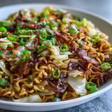 Quick weeknight Fried Cabbage Ramen stir fry garnished with scallions on a rustic plate ready to eat.