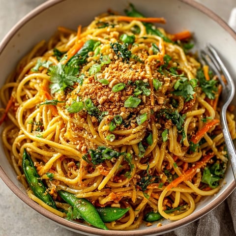 Ginger Garlic Noodles with Crystallized Ginger Crunch served in a bowl, showcasing glossy noodles and vibrant vegetables.