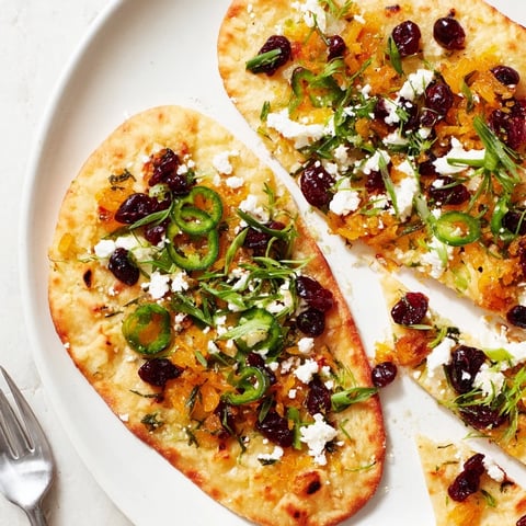 A warm ginger cranberry jalapeño flatbread, topped with vibrant herbs and cheese.  
