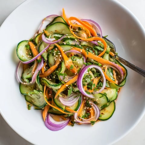 Refreshing cucumber salad remix topped with sesame seeds and vibrant colors.  