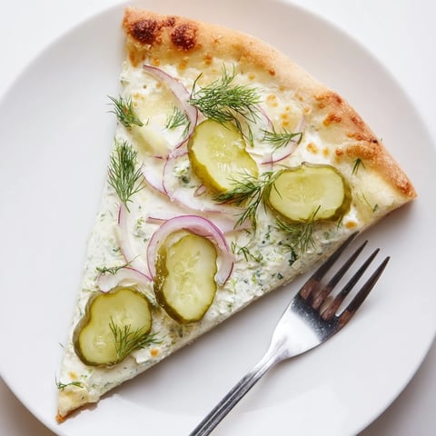 Tangy Pickle Pizza topped with creamy sauce, dill, and golden melted mozzarella.  