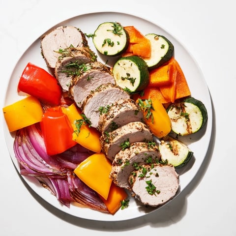 Tender roasted garlic pork tenderloin surrounded by colorful, caramelized vegetables, ready to serve.