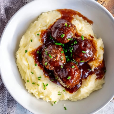 BBQ Meatballs & Mashed Potatoes: Tender, saucy meatballs resting atop fluffy, creamy mashed potatoes with a delicious aroma.
