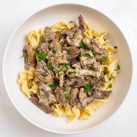 Creamy Mushroom Beef Stroganoff: A comforting bowl of tender beef and creamy mushroom sauce atop egg noodles.