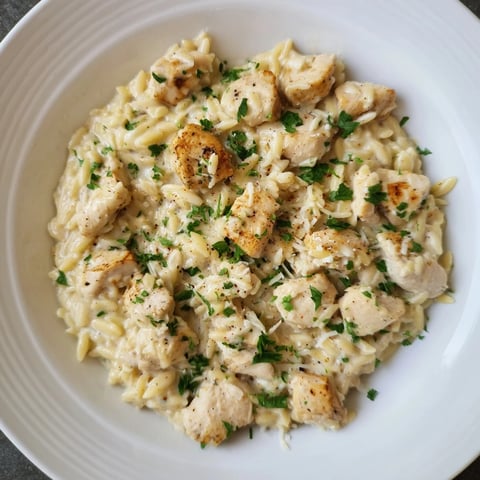 A photo of the creamy One-Pot Cajun Chicken Alfredo Orzo, with parmesan cheese and parsley garnish.