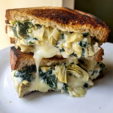 Gooey Spinach Artichoke Grilled Cheese oozing with creamy filling, served on golden sourdough for a comforting lunch.
