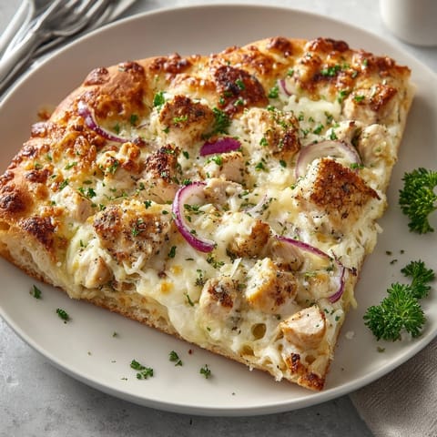 Sliced Garlic Alfredo Chicken Pizza served hot, creamy sauce and tender chicken inviting each bite.
