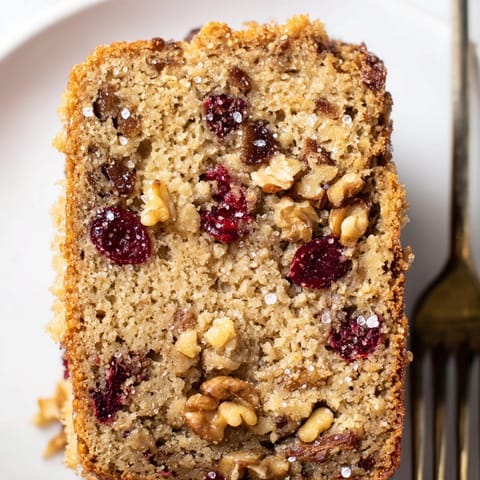 Homemade Cinnamon Cranberry Breakfast Loaf with a crunchy sugar topping, ready to slice.