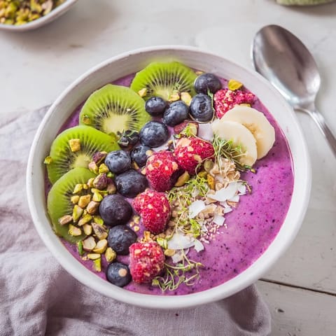 Colorful smoothie bowls featuring pistachios and kiwi, topped with crunchy granola.  