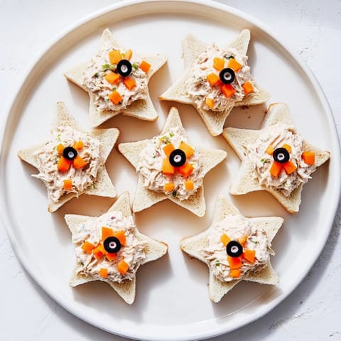 These Mini Starfish Sandwiches, ocean-themed appetizers, feature olive eyes and carrot star points.