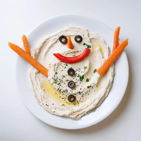 Creamy melted snowman hummus, a colorful platter with carrot nose and bell pepper scarf.