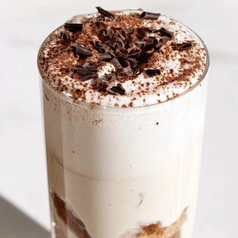 A close-up of a finished Tiramisu Latte, showcasing the beautiful layers, from biscuit crumb to cream.