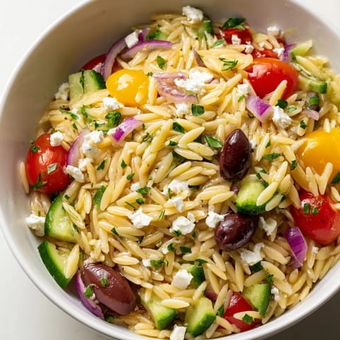Fork-ready Greek Orzo Salad tossed with vibrant herbs, briny Kalamata olives, and a bright lemon-oregano dressing, ideal for summer potlucks.