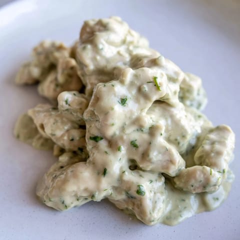 Green Goddess Chicken Salad served in a rustic bowl, garnished with avocado slices and cherry tomatoes.  