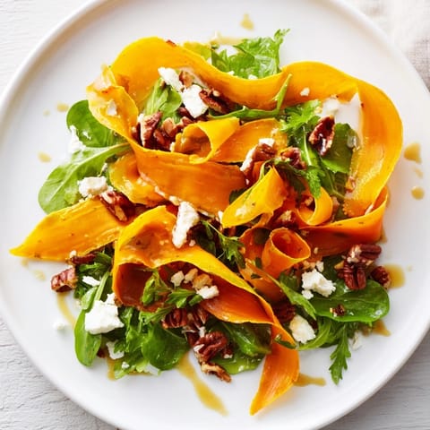 Tender roasted carrot ribbons artfully arranged on vibrant greens with crumbled feta and toasted pecans, drizzled with glossy honey–mustard dressing.