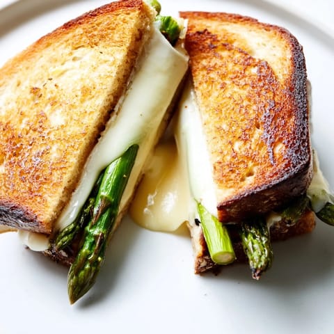 Asparagus & Brie Grilled Cheese, sliced to reveal tender charred asparagus and creamy melted Brie interior.