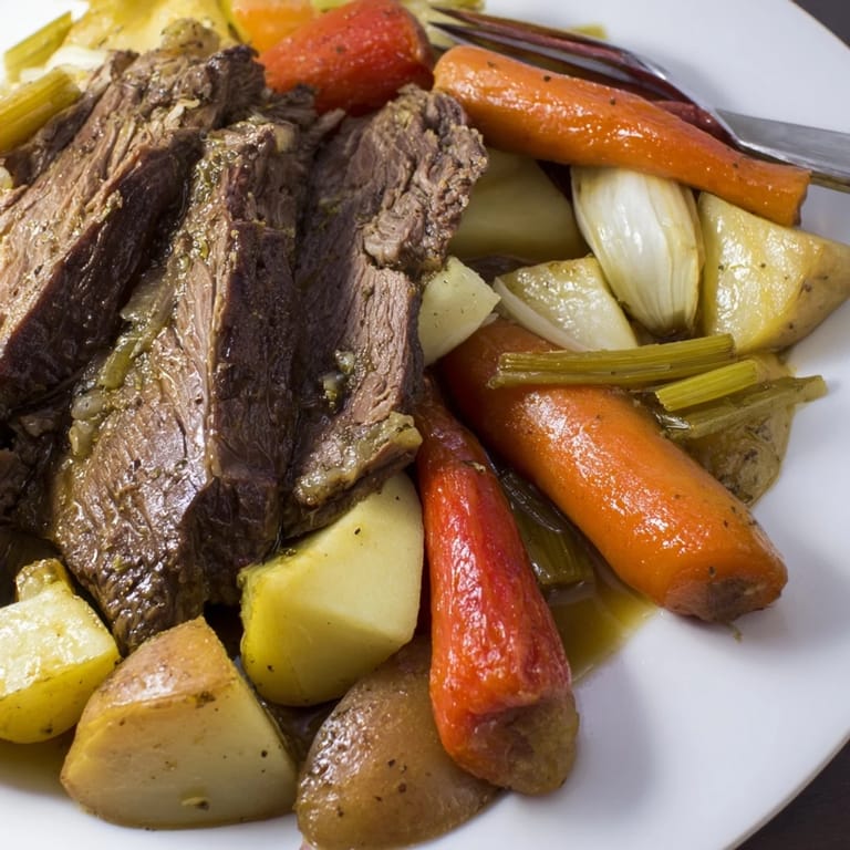 Succulent Sunday Pot Roast surrounded by vibrant roasted carrots and potatoes on a plate.  