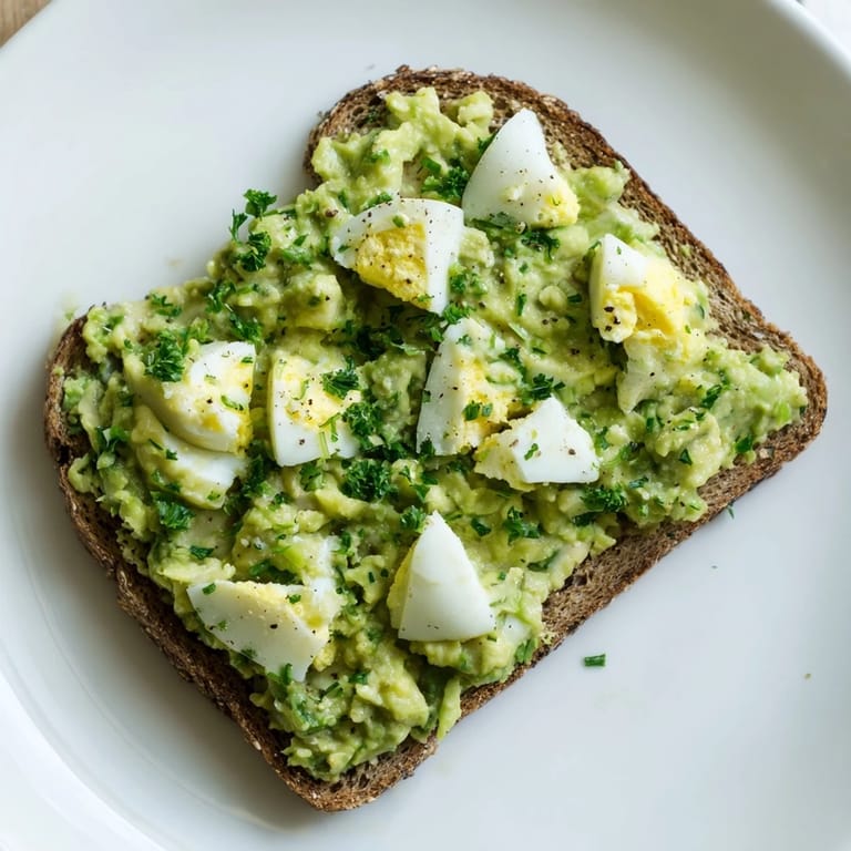 Freshly made avocado egg smash, glistening with lemon juice, ready to top whole-wheat toast.