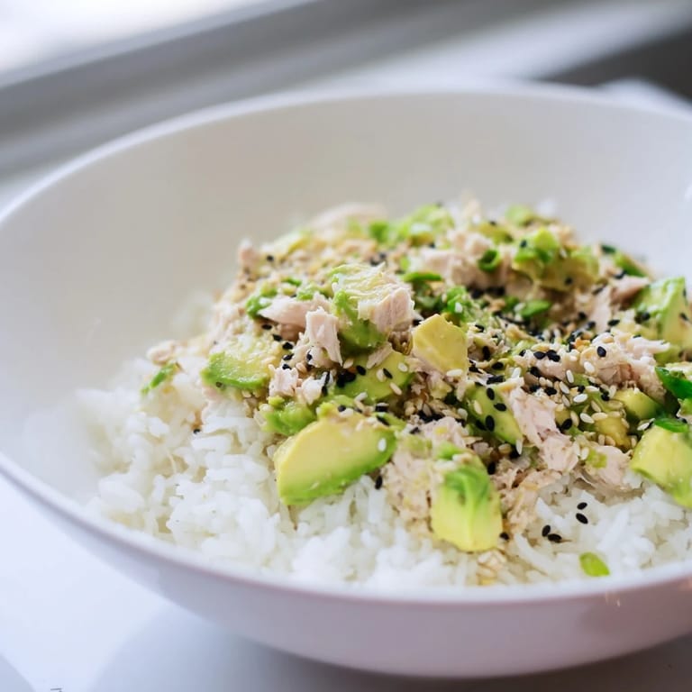A close-up of a vibrant Tuna Avocado Rice Bowl featuring tender tuna, ripe avocado slices, and crunchy nori strips over fluffy jasmine rice.
