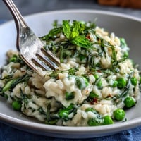 A bowl of creamy spring pea and mint risotto topped with freshly grated Parmesan and a sprinkle of lemon zest.